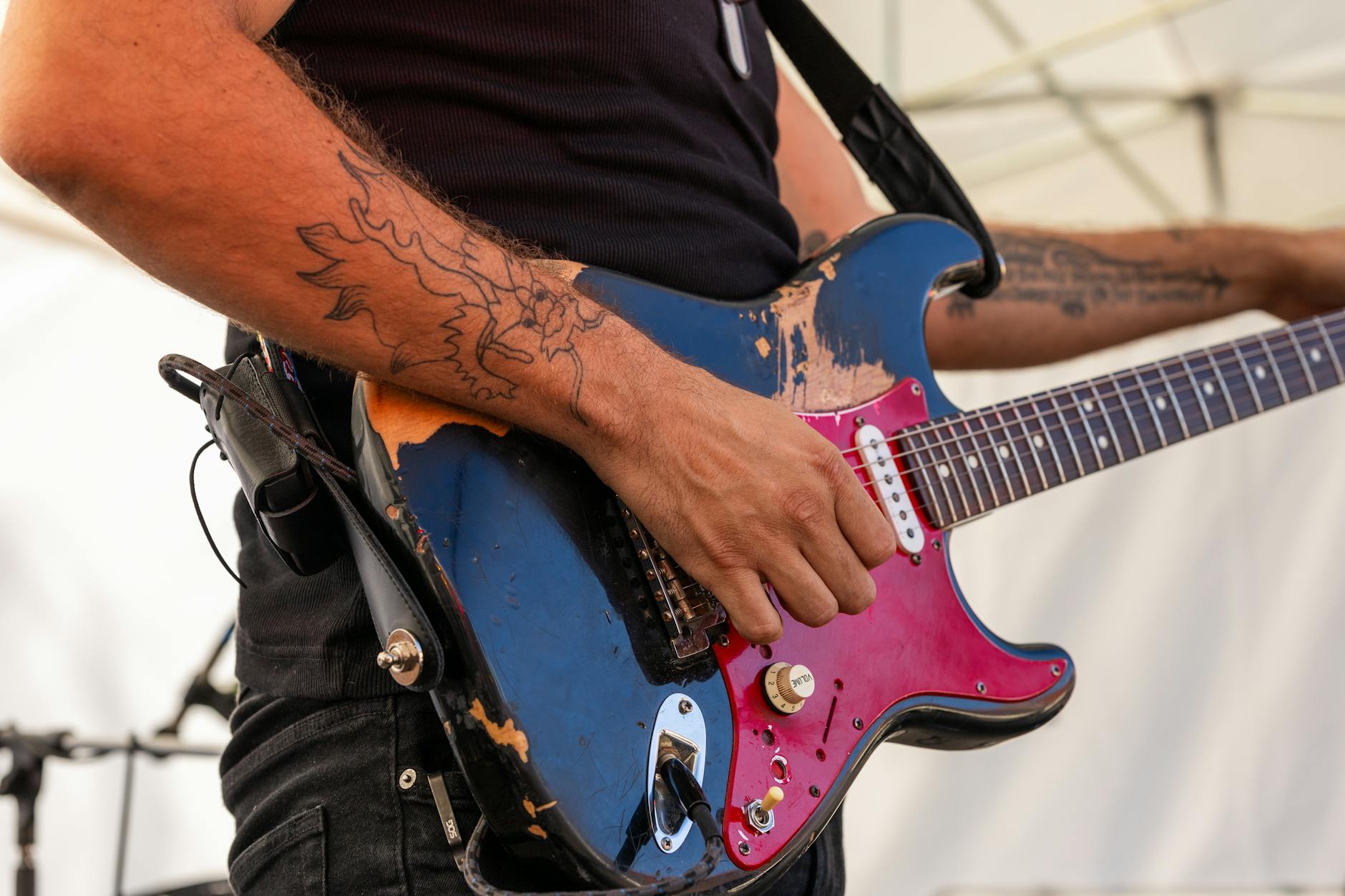 a man with tattoos playing an electric guitar